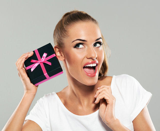 Excited young woman holding gift box